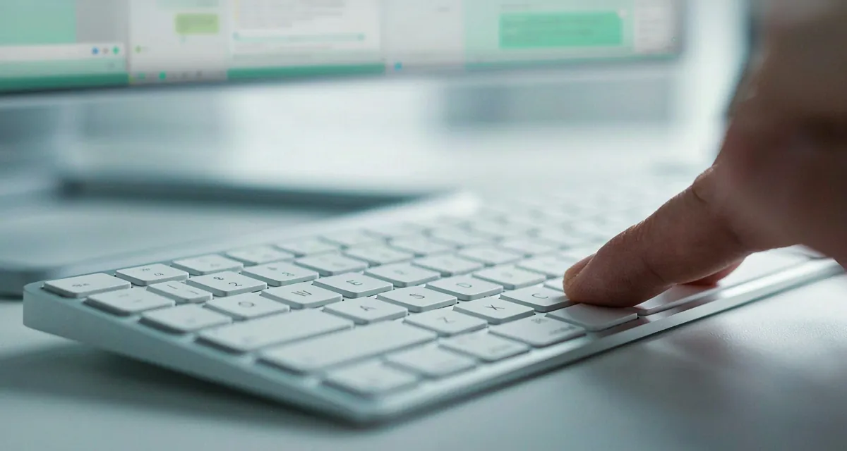 Enter WhatsApp Web: dedo sobre la tecla Enter de un teclado de computadora frente a la pantalla con una conversación de chat abierta (2026)